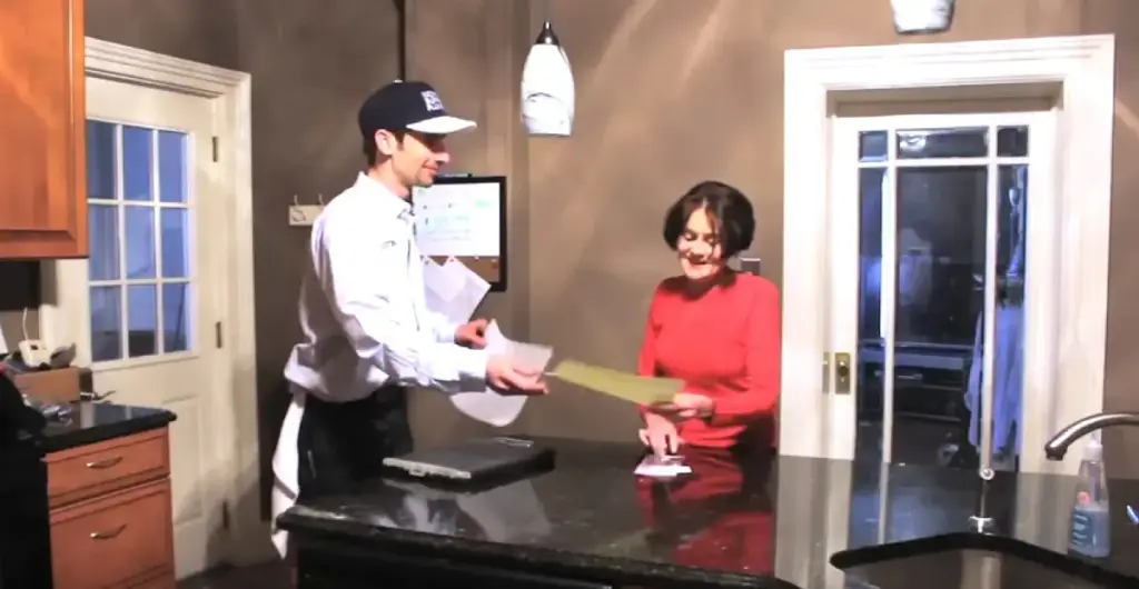 A Michigan Supreme plumber going over the job with a homeowner at her kitchen counter